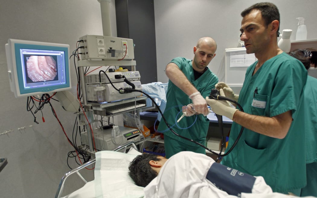 A doctor performs a colonoscopy on a patient at a hospital in France. In New Zealand, demand for the procedure that looks for bowel cancer continues to outstrip supply.