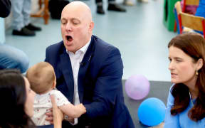 National Party leader Christopher Luxon holds a baby as deputy leader Nicola Willis watches.