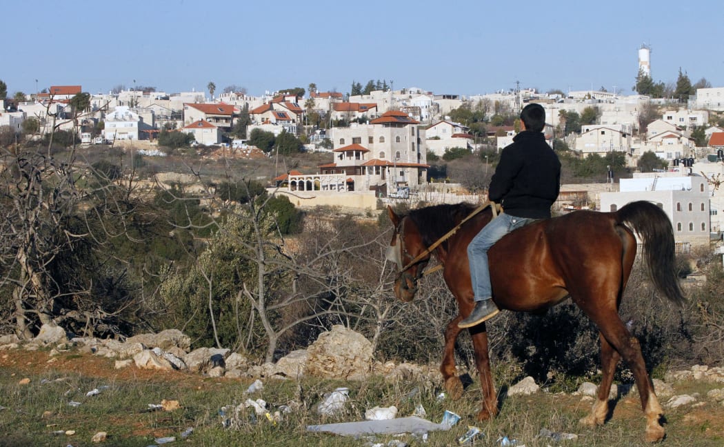 A Palestinian boy riding his horse past the Israeli settlement of Givat Harsina.