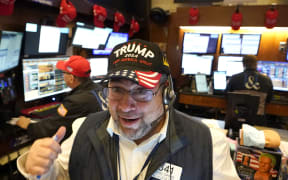 Trader Michael Capolino wears a Trump hat as he works on the floor of the New York Stock Exchange (NYSE) ahead of the opening bell on November 6, 2024, in New York City. - Wall Street stocks surged in opening trading on Wall Street Wednesday after US voters sent Donald Trump back to the White House and delivered him a Republican Senate. Major indices were up 1.8 percent or more in the early going as hopes about expected tax cuts and regulatory easing more than offset worries about higher tariffs. (Photo by TIMOTHY A. CLARY / AFP)