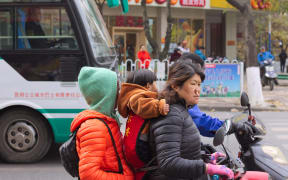 A family negotiates traffic on a scooter in Kunming, China.