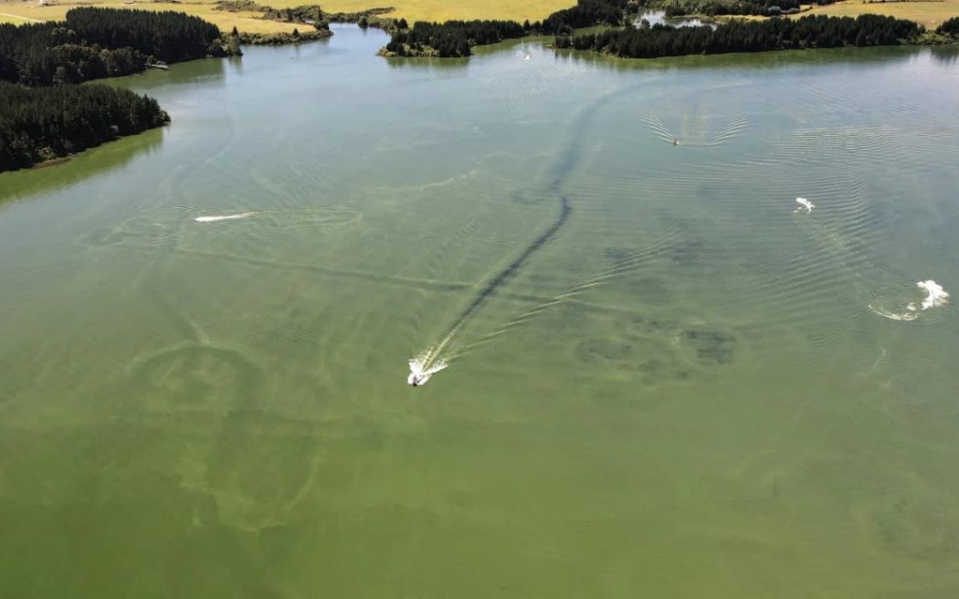 Drone shot of lake showing  jet boat leaving clear trail through sludgy algae filled lake