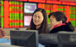 Concerned Chinese investors look at prices of shares (red for price rising and green for price falling) at a stock brokerage house