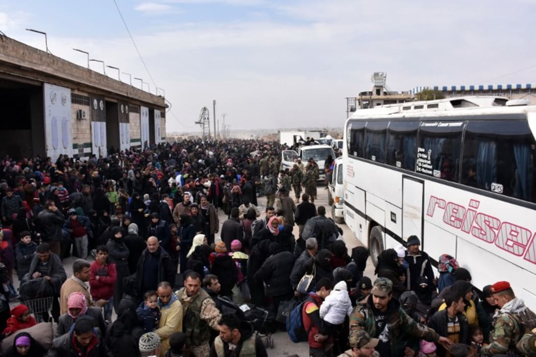 Syrian families, fleeing from various eastern districts of Aleppo, queue to get onto governmental buses on November 29, 2016 in the government-held eastern neighbourhood of Jabal Badro,