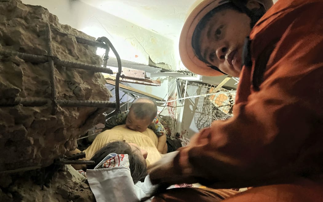 A rescue worker attempts to extract a mother and her child from a collapsed building in Naypyidaw on March 28, 2025, after an earthquake in central Myanmar. A powerful earthquake rocked central Myanmar on March 28, buckling roads in capital Naypyidaw, damaging buildings and forcing people to flee into the streets in neighbouring Thailand.