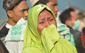 A woman cries as people look at the damages after an earthquake and a tsunami hit Palu, on Sulawesi Island.