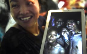 A happy family member shows the latest picture of the missing boys taken by rescue divers inside Tham Luang cave.