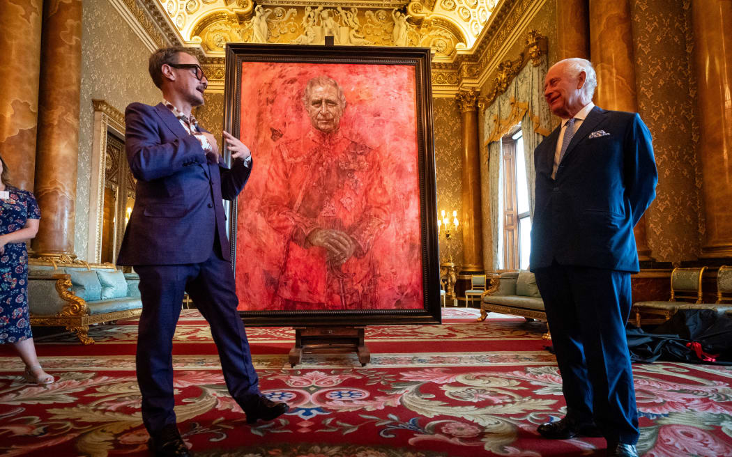 Britain's King Charles III (R) reacts as he stands alongside artist Jonathan Yeo, after unveiling an official portrait of himself wearing the uniform of the Welsh Guards, of which he was made Regimental Colonel in 1975, by artist Yeo, in the Blue Drawing Room at Buckingham Palace in London on May 14, 2024. The official portrait was commissioned in 2020 to celebrate the then Prince of Wales's 50 years as a member of The Drapers' Company in 2022. Artist Jonathan Yeo had four sittings with the King Charles III, beginning when he was Prince of Wales in June 2021 at Highgrove, and later at Clarence House. The last sitting took place in November 2023 at Clarence House. Yeo also worked from drawings and photography he took, allowing him to work on the portrait in his London studio between sittings. The canvas size - approximately 8.5 by 6.5 feet when framed - was carefully considered to fit within the architecture of Drapers' Hall and the context of the paintings it will eventually hang alongside. (Photo by...