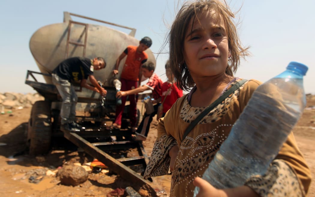 Young Iraqi Yazidi refugees fill bottles with water at the Newroz camp in Hasaka province, north eastern Syria.