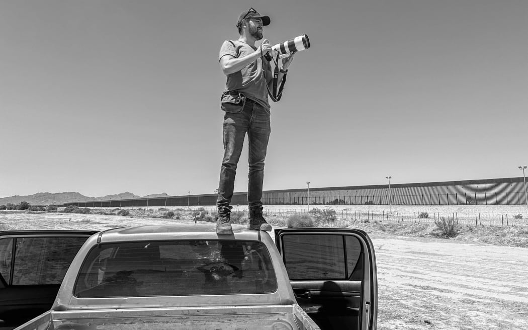 Image of Alejandro Cegarra standing on top of a truck with camera.