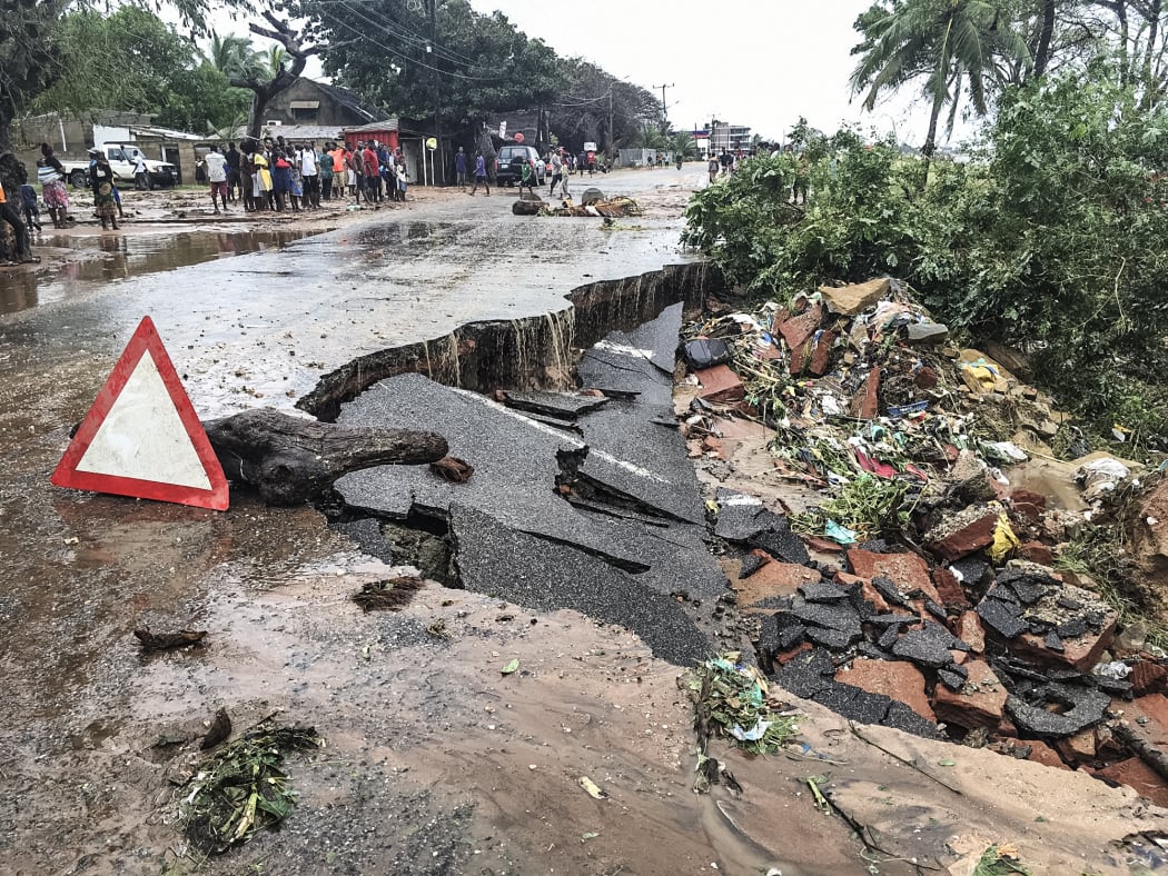 Residents stand next to a road partially destroyed by Cyclone Kenneth.