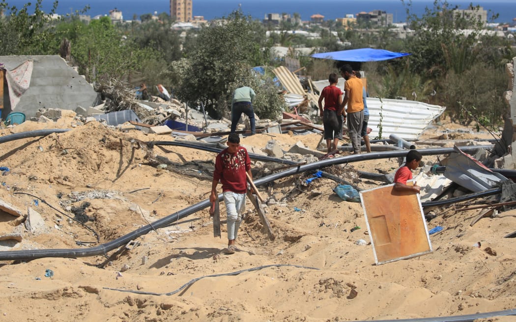 People look for salvageable items following an Israeli raid in al-Mawasi area in Rafah, on the southern Gaza Strip, on June 29, 2024, amid the ongoing conflict between Israel and the Palestinian militant Hamas movement. (Photo by Eyad BABA / AFP)