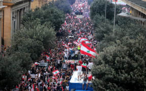 Thousands of Lebanese demonstrators wave their country's flag during a mass protest in Beirut demanding the fall of the government.