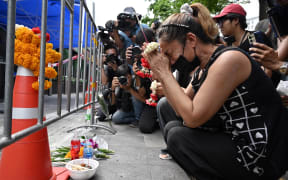 A woman, identified as Nid, prays for her deceased daughter Namtip Tubsook and her son-in-law Suwitcha Sirililung in front of the Rong Beer Na Lat Phrao bar in Bangkok on July 14, 2026. Investigators combed on July 13 through the wreckage of a huge fire at a Bangkok bar that killed at least 28 people, as relatives began the grim task of identifying the dead. (Photo by Lillian SUWANRUMPHA / AFP)