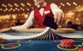 The croupier holds poker cards in his hands at a table in a casino.
