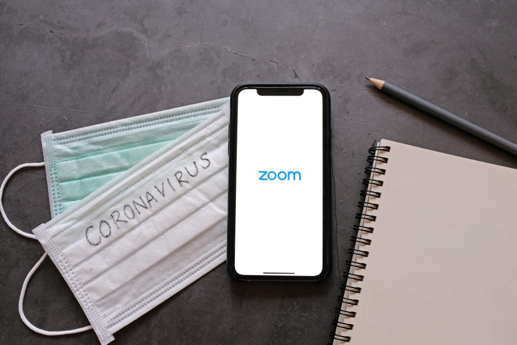 :Flat lay of smartphone showing zoom application and mask with notebook.