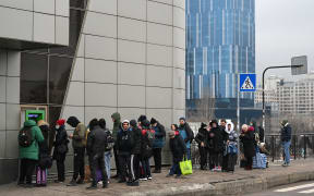 People line up to withdraw money at a cash dispenser in Kyiv in the morning of February 24, 2022.