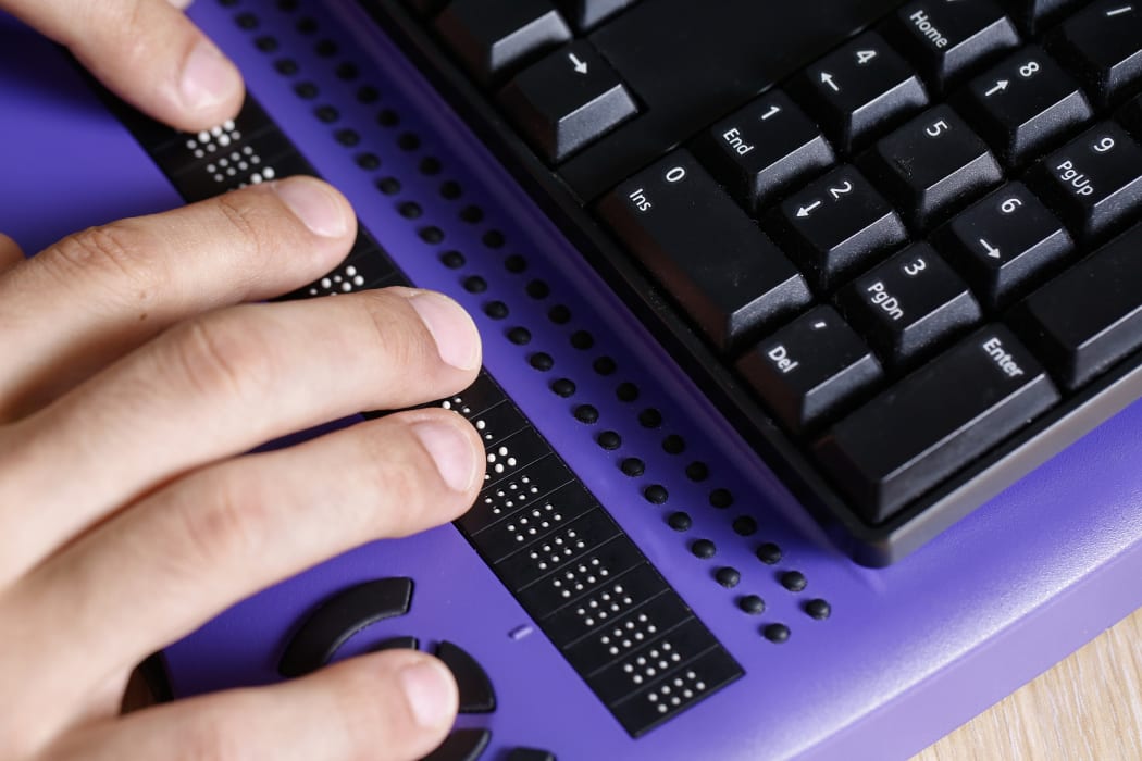 Blind person using computer with braille keyboard. Visual impairment, independent life concept.