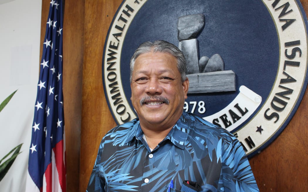 Tinian Mayor Edin Aldan stands in front of Tinian’s Commonwealth Seal.