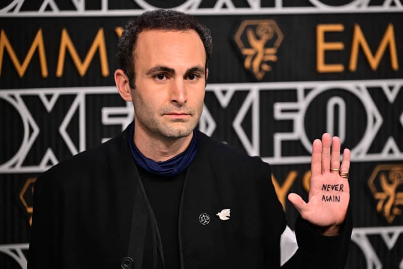 British actor Khalid Abdalla shows the message "Never Again" painted in his palm as he arrives for the 75th Emmy Awards at the Peacock Theatre at L.A. Live in Los Angeles on January 15, 2024. (Photo by Frederic J. Brown / AFP)
