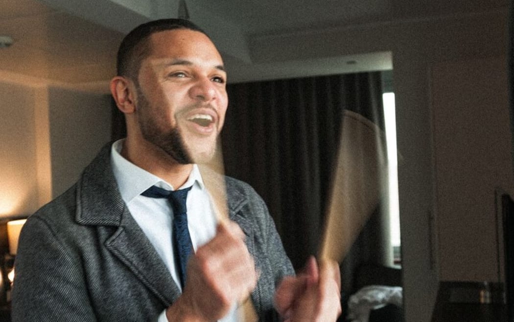 Drummer Myele Manzanza standing in a hotel room playing air drums.
