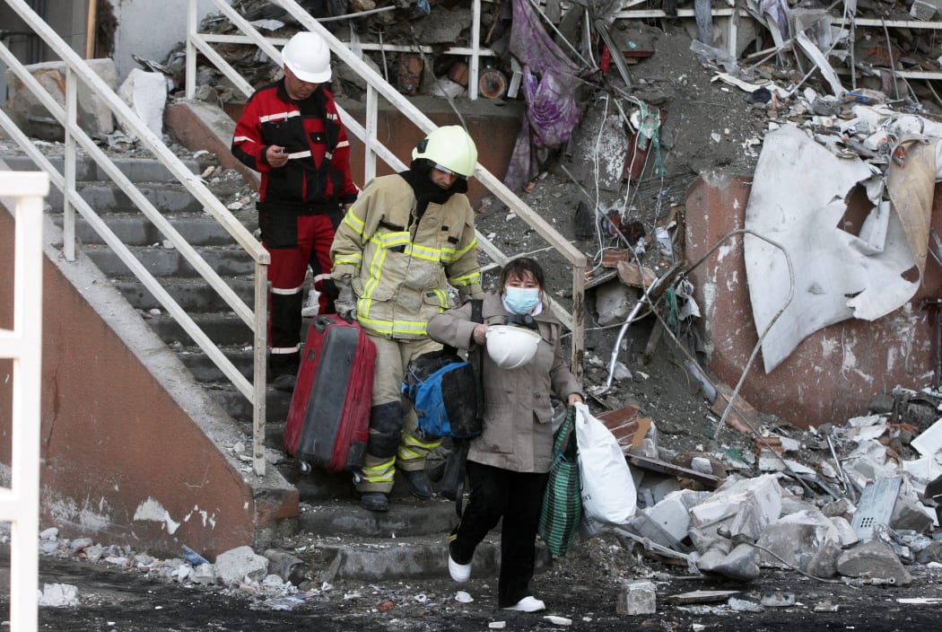 Rescue workers escort a local resident as she leaves a residential building which was hit by a missile strike in Odesa, Ukraine 24 April, 2022.