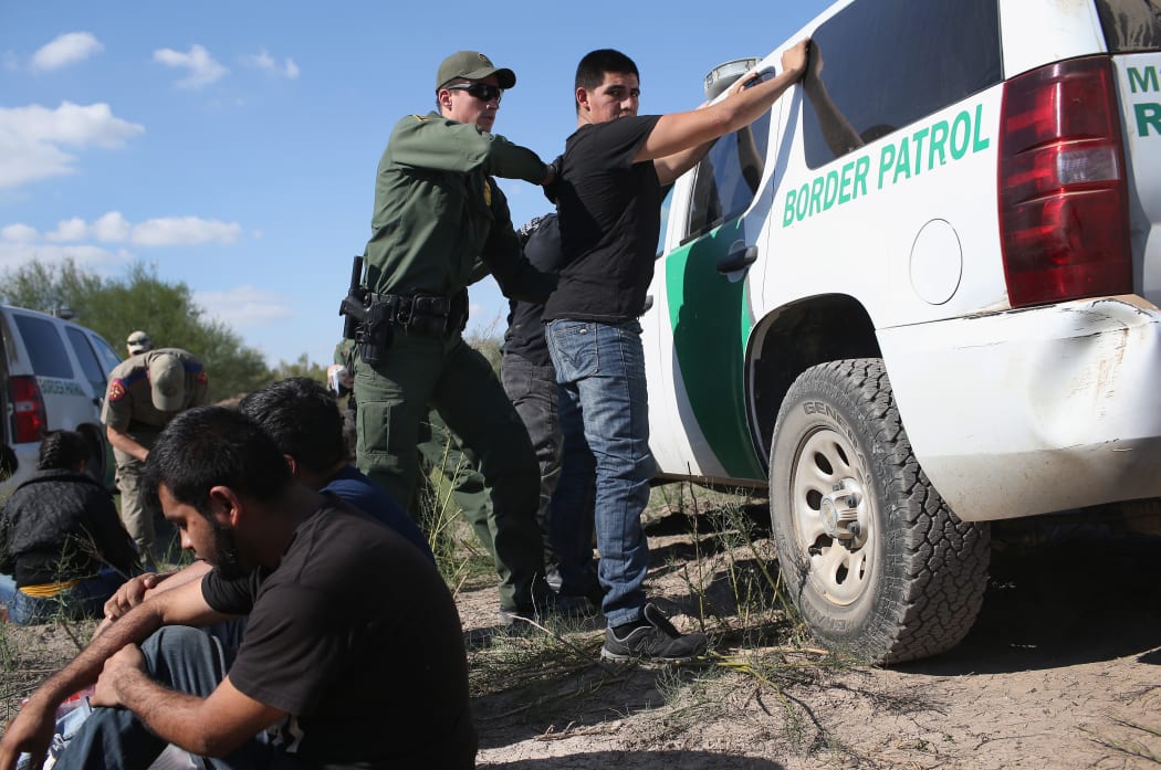 A US Border Patrol officer searches an undocumented immigrant after he illegally crossed the US-Mexico border and was caught in December 2015.