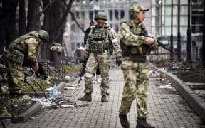 Russian soldiers walks along a street in Mariupol as Russian troops intensify a campaign to take the strategic port city.
