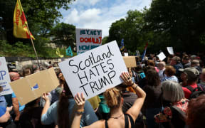 Demonstrators hold placards during a 'Stop Trump Coalition' protest near the US Consulate building in Edinburgh, Scotland on July 26, 2025. US President Donald Trump landed in Scotland on July 25, for a five-day visit set to mix diplomacy, business and leisure. (Photo by SCOTT HEPPELL / AFP)
