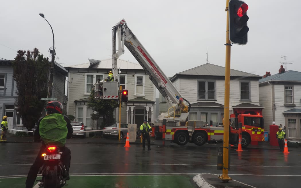 Fire fighters and police tending to a loose sheet of corrugated iron on the roof of a house on the Terrace in Wellington during a storm on 1 May, 2025.