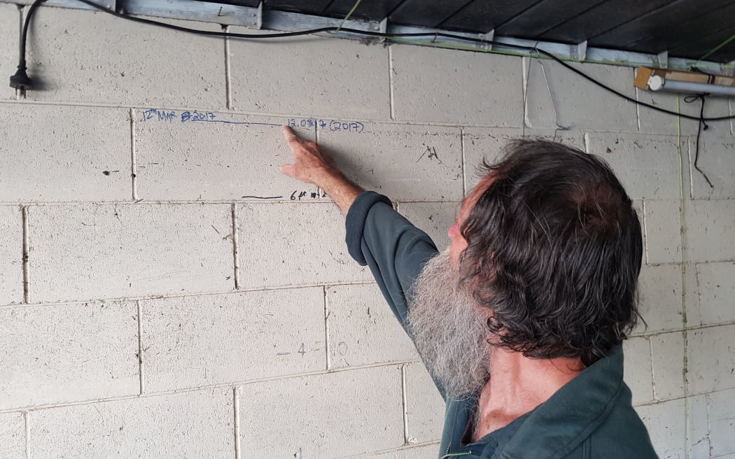 Rodney Johnson has marked off how high the floodwaters reached inside his garage.