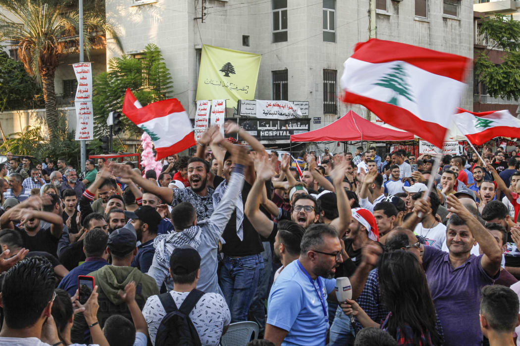 Lebanese anti-government protesters celebrate the resignation of Prime Minister Saad Hariri in the southern city of Sidon on October 29, 2019 on the 13th day of anti-government protests.
