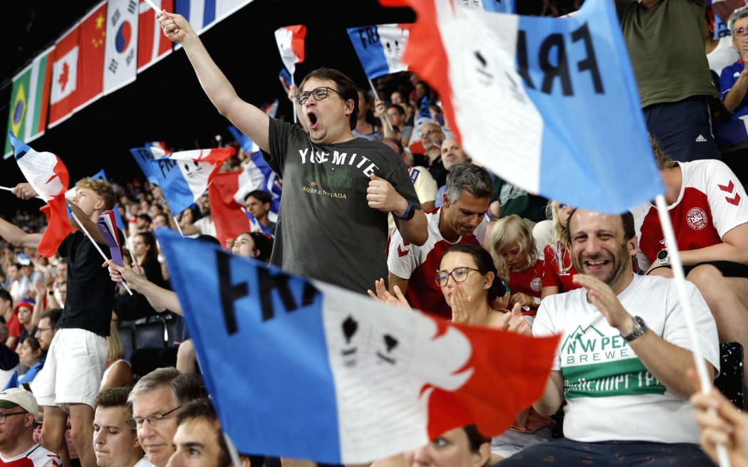 Supporters of France's Toma Junior Popov celebrate his win against Indonesia's Anthony Sinisuka Ginting in their men's singles badminton group stage match during the Paris 2024 Olympic Games at Porte de la Chapelle Arena in Paris on July 31, 2024. (Photo by Luis TATO / AFP)