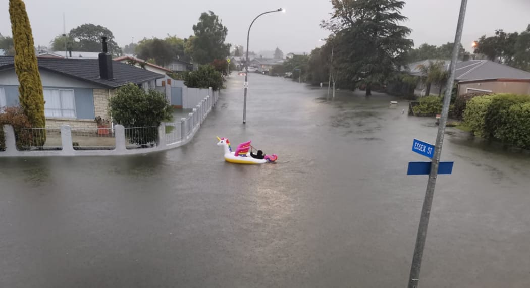 A man paddles an inflatable unicorn up the road, on Essex Street, Napier.