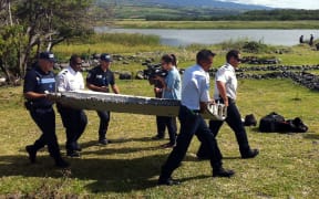 Police carry debris from an aircraft found on the Indian Ocean island of La Reunion.