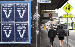 People walk past a sign encouraging people to get vaccinated in Melbourne on August 31, 2021 as the city experiences it's sixth lockdown as it battles an outbreak of the Delta variant of coronavirus.