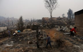 People work to clean up the debris after a forest fire devastated Santa Olga, 240 kilometres south of Santiago