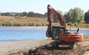 A digger on a stopbank in Mataura, Southland.