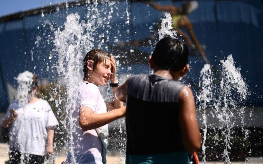 Children play in a fountain as they cool down from the heat in Melbourne.