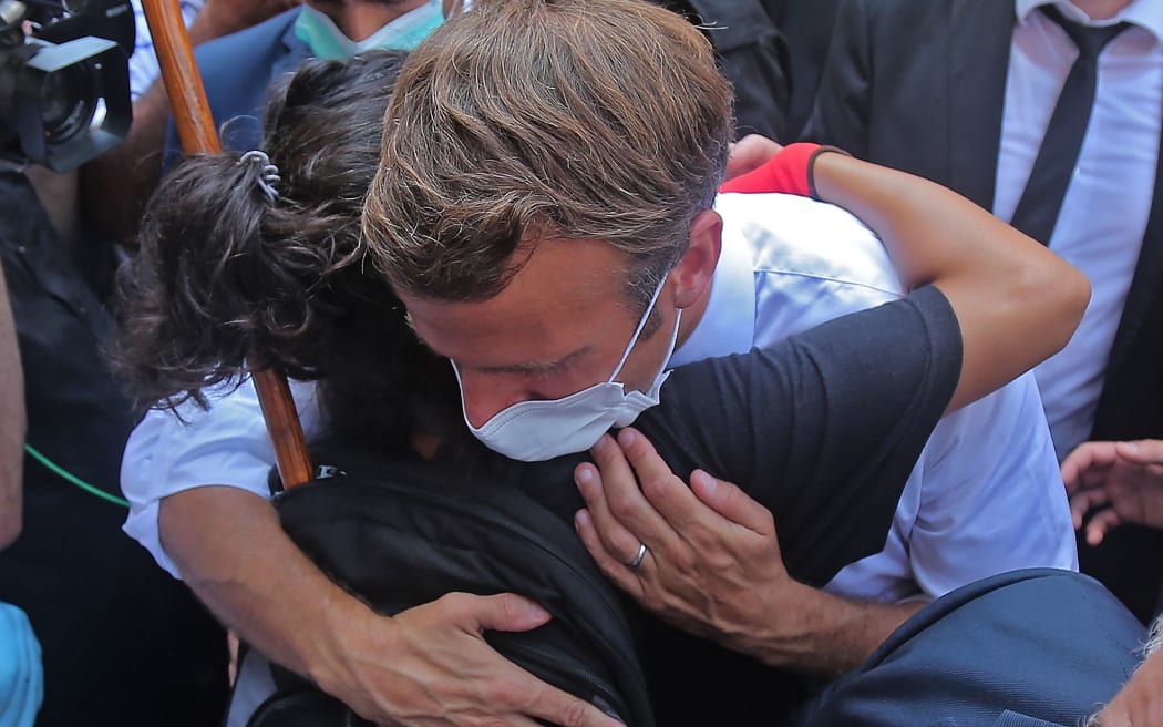 A Lebanese youth hugs French President Emmanuel Macron during a visit to the Gemmayzeh neighborhood, which has suffered extensive damage due to a massive explosion in the Lebanese capital, on August 6, 2020. - French President Emmanuel Macron visited shell-shocked Beirut,