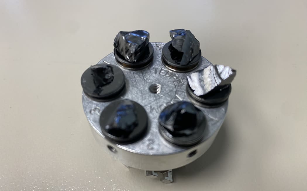 Six obsidian shards are prepared for use inside a metal container for use inside a electron microscope.