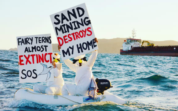 Pakiri seabed sand mining protestors voice their opposition as a McCallum Bros' sand mining ship moves by.