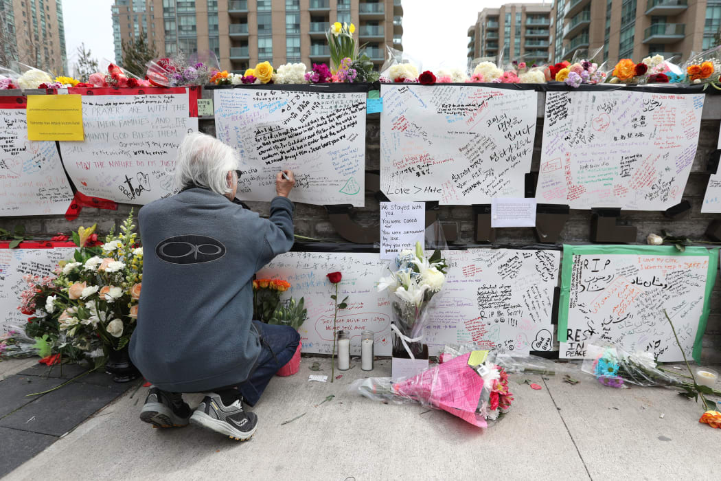 Jack Young leaves a notes at a makeshift memorial for victims in the van attack in Toronto, Ontario.