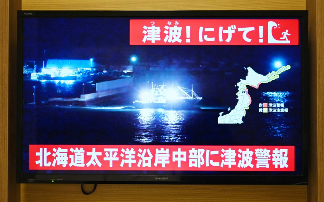 An advisory reading "Tsunami! Run!" (top) and "Tsunami warning issued for central Hokkaido’s Pacific Coast" flashes over live TV coverage on a screen in Sapporo, in Japan’s northern Hokkaido prefecture on 8 December 2025. Japan recorded a 40-centimetre tsunami after a 7.5-magnitude quake on 8 December.