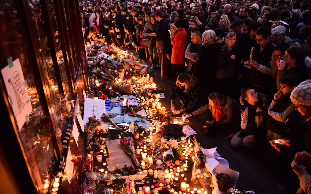 People light candles at a makeshift memorial in front of Le Carillon restaurant, one of the site of the attacks in Paris.