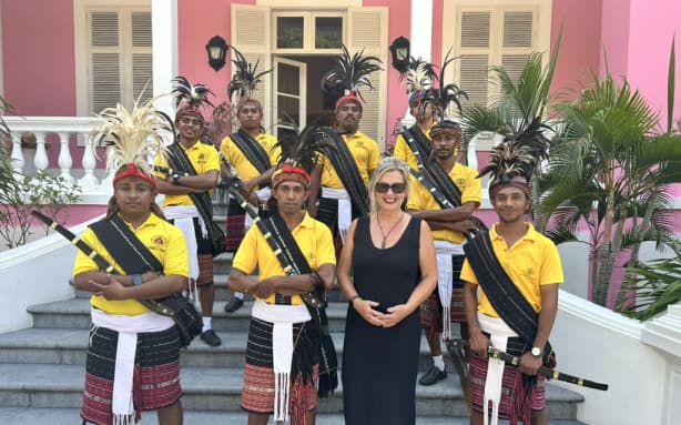 Anna Thomas outside the Pink Palace with traditional Timorese guards.