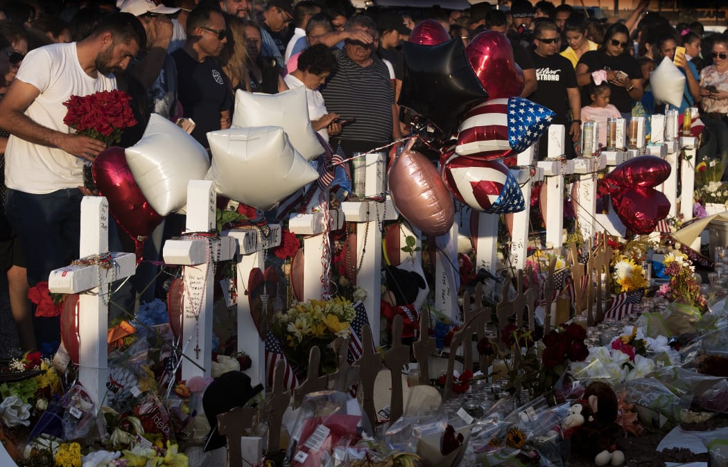 People pray and pay their respects at the makeshift memorial for victims of the shooting that left a total of 22 people dead in El Paso.
