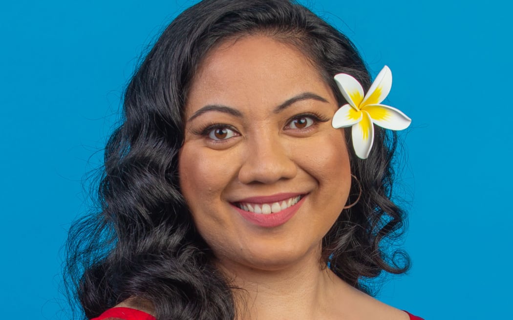 Susana looks directly forward smiling and wearing a flower behind her left ear