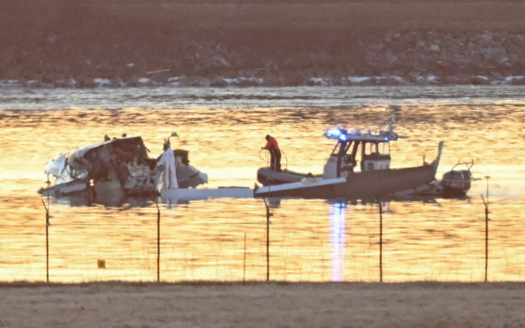 Part of the wreckage is seen as rescue boats search the waters of the Potomac River after a plane on approach to Reagan National Airport crashed into the river outside Washington, DC, on January 30, 2025. A regional jet from Kansas crashed into Washington's Potomac River after colliding mid-air with a military helicopter near Reagan National Airport, officials said January 29, prompting a major emergency response and grounding all flights. (Photo by ANDREW CABALLERO-REYNOLDS / AFP)