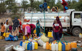 In this file photo taken on August 26, 2021 Yemeni women and children fill their jerricans with water from a tanker in the southwestern Taez Governorate's Al-Maafer district, amidst severe water shortage.